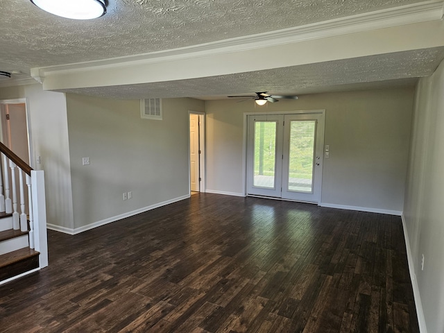 empty room with a textured ceiling, wood finished floors, a ceiling fan, baseboards, and stairs