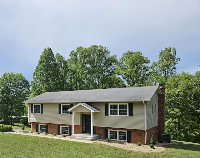 split foyer home featuring a front yard, a chimney, central air condition unit, and brick siding