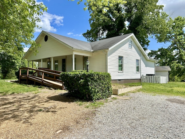 view of side of property featuring gravel driveway, covered porch, and crawl space