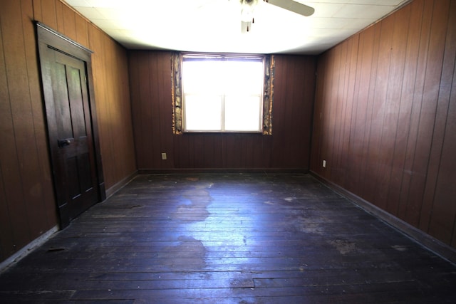 unfurnished room featuring dark wood-style floors, a ceiling fan, and wooden walls