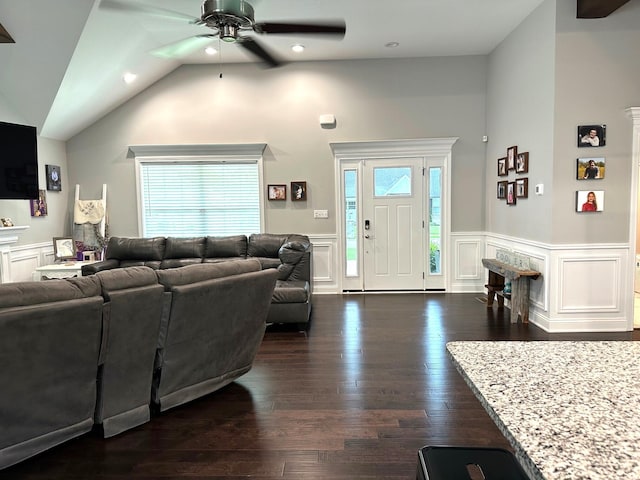 living room featuring ceiling fan, a wainscoted wall, vaulted ceiling, a decorative wall, and dark wood-style flooring