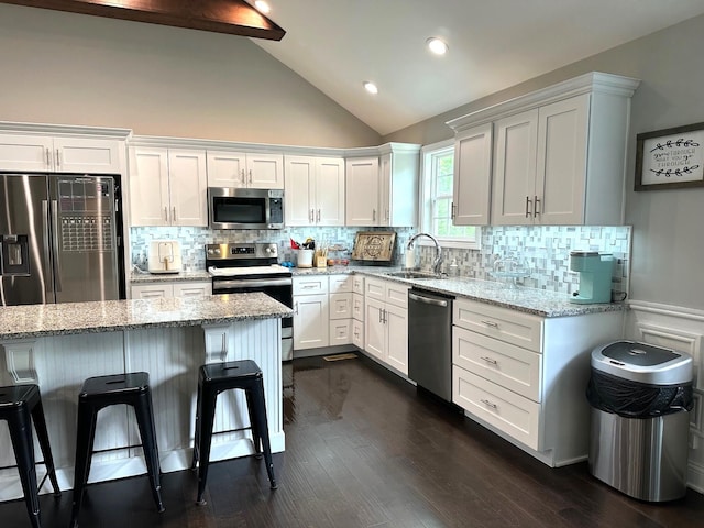 kitchen featuring stainless steel appliances, a sink, a breakfast bar, white cabinets, and recessed lighting