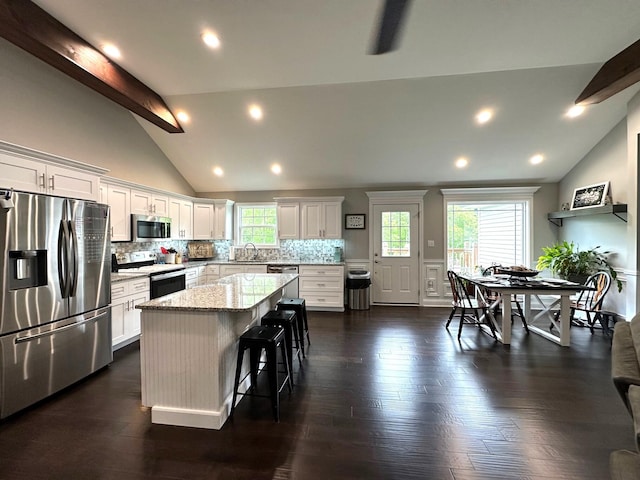 kitchen featuring stainless steel appliances, a center island, tasteful backsplash, white cabinets, and light stone counters