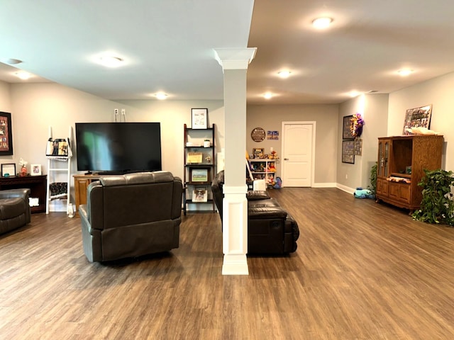 living room with wood finished floors, baseboards, and decorative columns