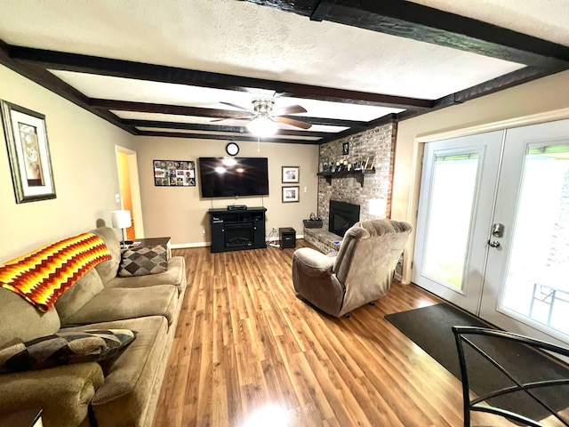4758 Cloverlick Rd, Cumberland, KY 40823 - living room featuring a ceiling fan, french doors, light wood-style floors, a large fireplace, and beamed ceiling