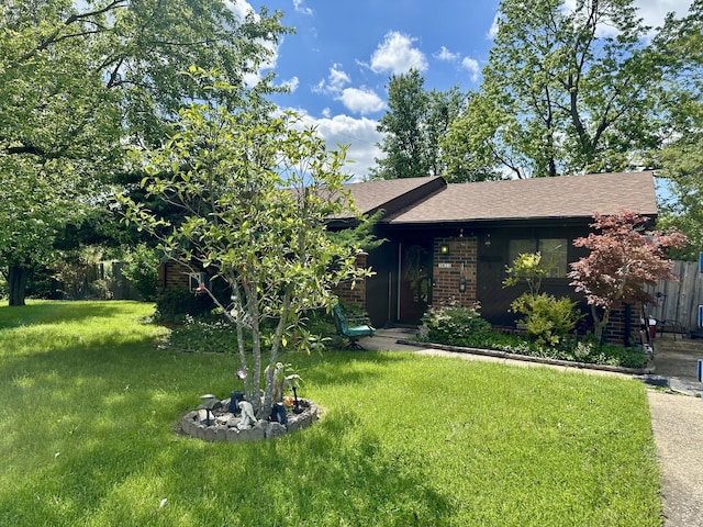 view of front of house featuring a front lawn, brick siding, and a shingled roof