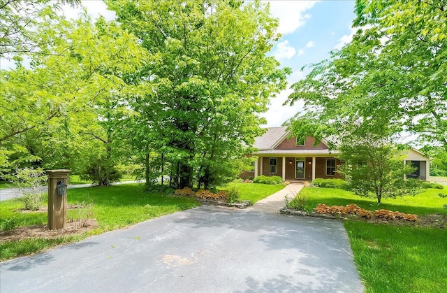 view of property hidden behind natural elements with a porch and a front lawn
