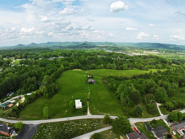 aerial view of property and surrounding area with mountains and a heavily wooded area