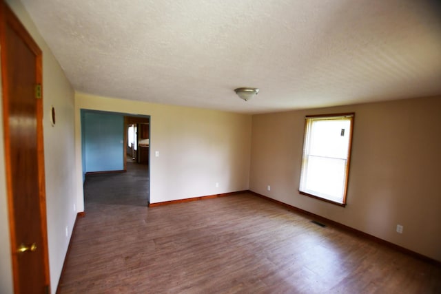 unfurnished room featuring wood finished floors, a textured ceiling, and baseboards