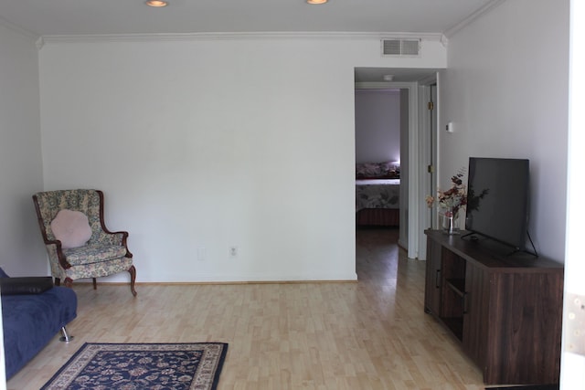 sitting room featuring light wood-style floors, crown molding, baseboards, and recessed lighting