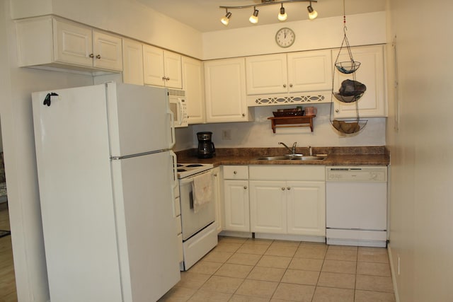 kitchen featuring white appliances, a sink, dark countertops, white cabinetry, and light tile patterned floors
