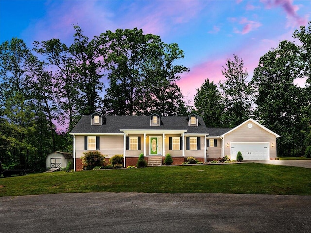 cape cod house with a porch, a storage shed, concrete driveway, a front lawn, and a garage