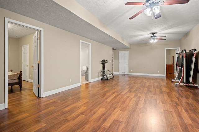 unfurnished living room featuring a textured ceiling, ceiling fan, wood finished floors, and baseboards