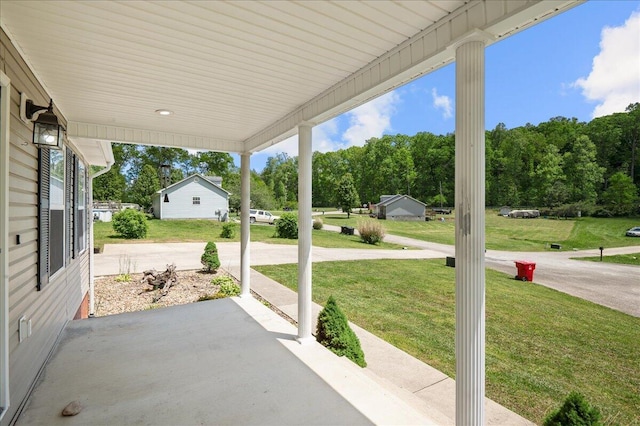 view of patio with a porch and view of wooded area