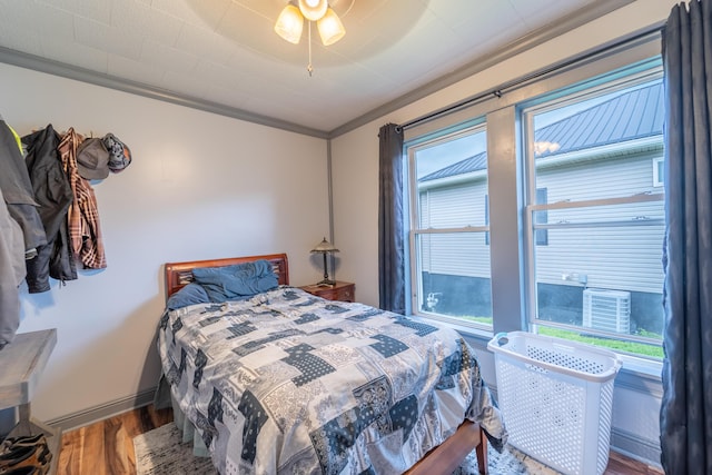 bedroom with wood finished floors, crown molding, baseboards, and a ceiling fan