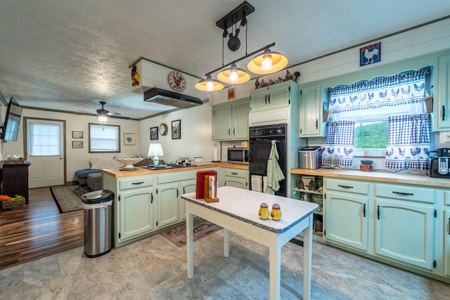 kitchen with a textured ceiling, green cabinetry, ceiling fan, cooktop, and stainless steel microwave