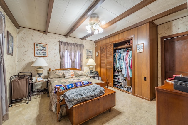 bedroom featuring carpet flooring, beamed ceiling, a closet, and wallpapered walls