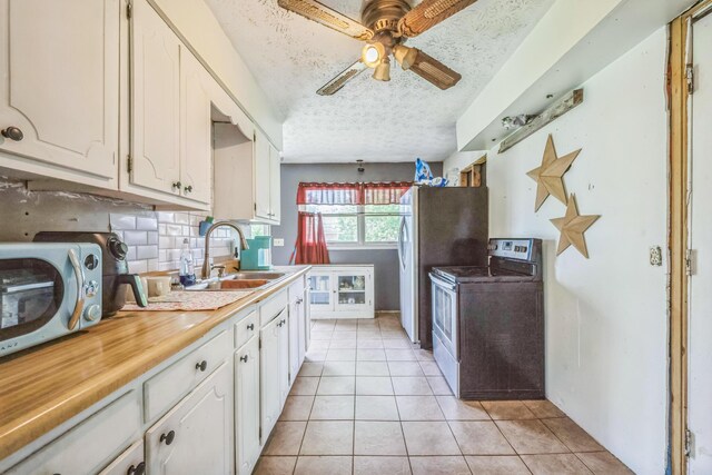3202 W Cumberland Ave, Middlesboro, KY 40965 - kitchen featuring stainless steel range with electric stovetop, a sink, decorative backsplash, a textured ceiling, and light tile patterned floors