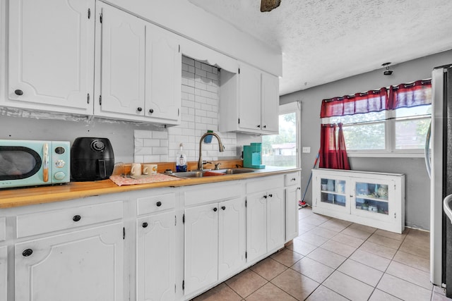 3202 W Cumberland Ave, Middlesboro, KY 40965 - kitchen featuring a sink, white cabinets, light tile patterned flooring, light countertops, and tasteful backsplash