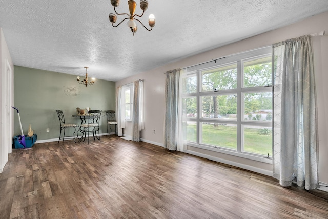 3202 W Cumberland Ave, Middlesboro, KY 40965 - unfurnished dining area featuring a chandelier, a textured ceiling, wood finished floors, and baseboards