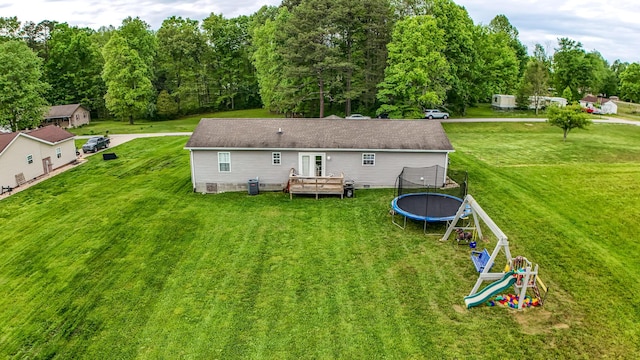 rear view of property with a trampoline, a deck, crawl space, and a lawn