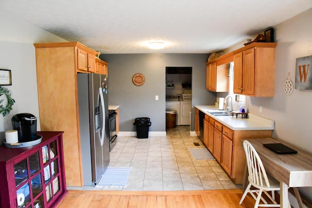 kitchen featuring stainless steel fridge with ice dispenser, washer and clothes dryer, a sink, light countertops, and dishwasher