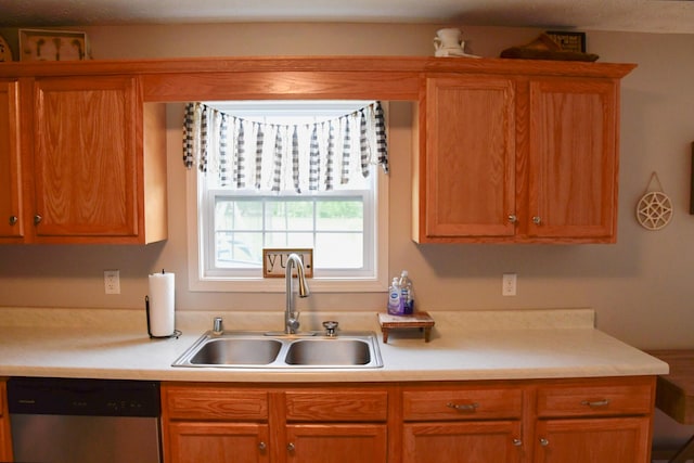 kitchen with a sink, dishwasher, light countertops, and brown cabinetry