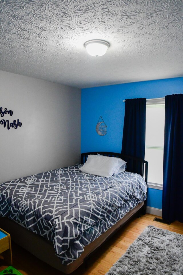 bedroom with wood finished floors and a textured ceiling