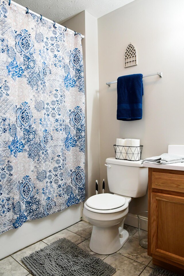bathroom featuring tile patterned floors, toilet, vanity, baseboards, and shower / tub combo with curtain