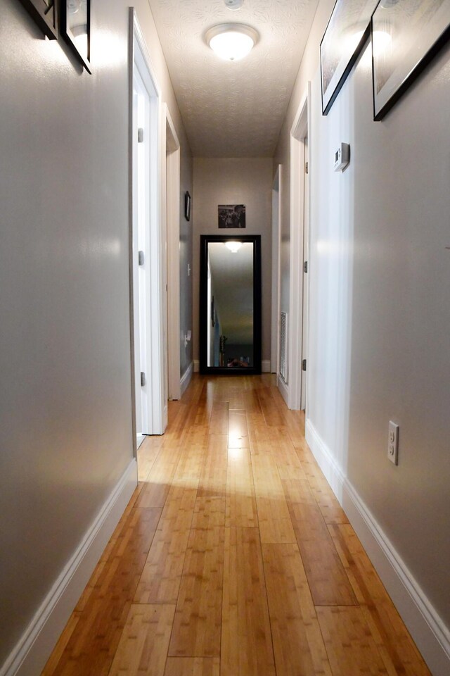 corridor featuring light wood-type flooring and baseboards
