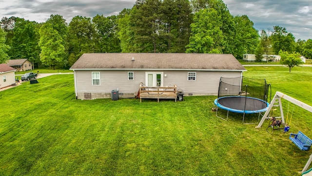 back of property with a deck, a trampoline, crawl space, and a yard