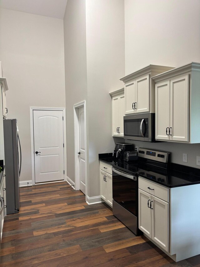 875 Ridgeview Dr, Frankfort, KY 40601 - kitchen featuring appliances with stainless steel finishes, a towering ceiling, dark countertops, dark wood-style floors, and baseboards