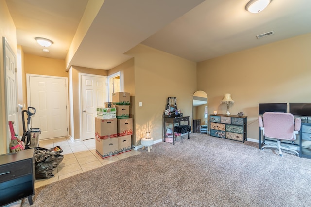office featuring baseboards, light colored carpet, light tile patterned floors, and arched walkways