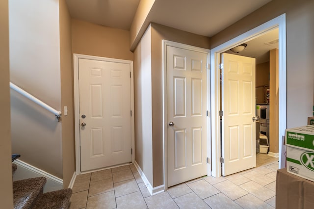 hall with light tile patterned floors, stairway, and baseboards