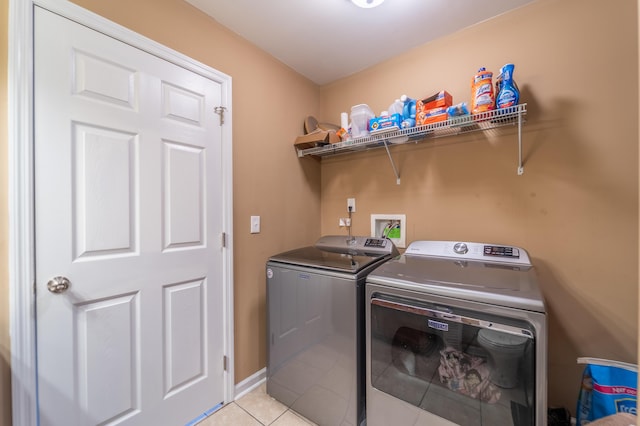 laundry room featuring washing machine and dryer, light tile patterned floors, and baseboards