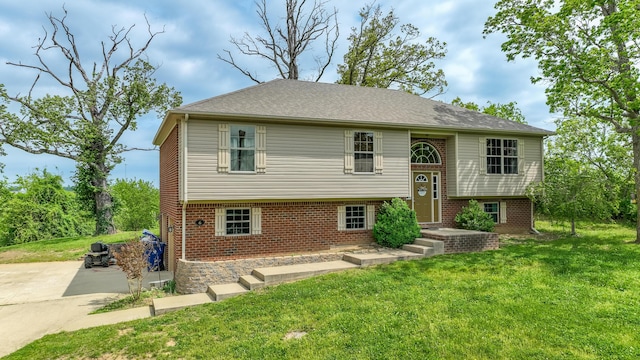 split foyer home featuring a front yard and brick siding