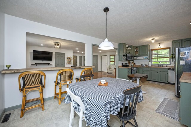 kitchen featuring appliances with stainless steel finishes, green cabinets, a sink, light flooring, and light countertops