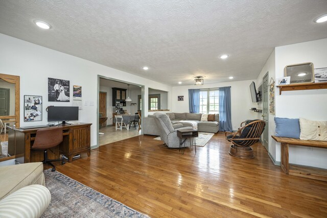 living room featuring wood finished floors, a textured ceiling, recessed lighting, and baseboards