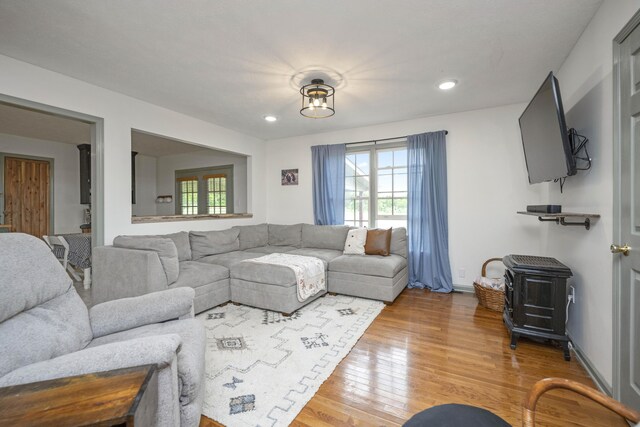 living room featuring wood finished floors, recessed lighting, a wood stove, and baseboards