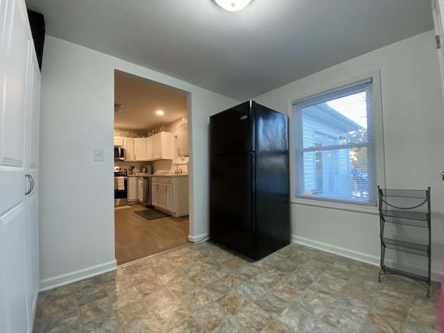 kitchen featuring stainless steel appliances, plenty of natural light, baseboards, and white cabinetry