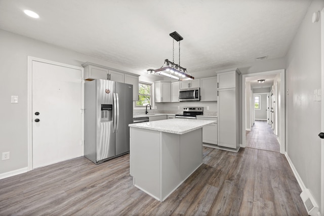 kitchen featuring stainless steel appliances, dark wood finished floors, a center island, pendant lighting, and recessed lighting