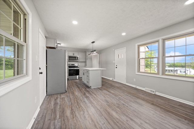kitchen featuring stainless steel appliances, recessed lighting, light countertops, dark wood-type flooring, and a kitchen island