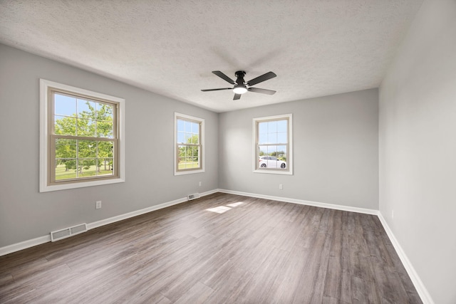 spare room with dark wood-style flooring, a textured ceiling, ceiling fan, and baseboards