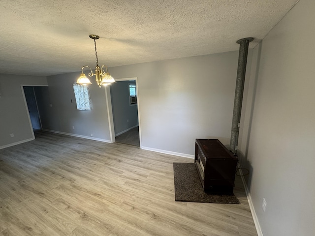 357 Powell Rd, Clay City, KY 40312 - unfurnished dining area with light wood finished floors, baseboards, a textured ceiling, a wood stove, and a chandelier