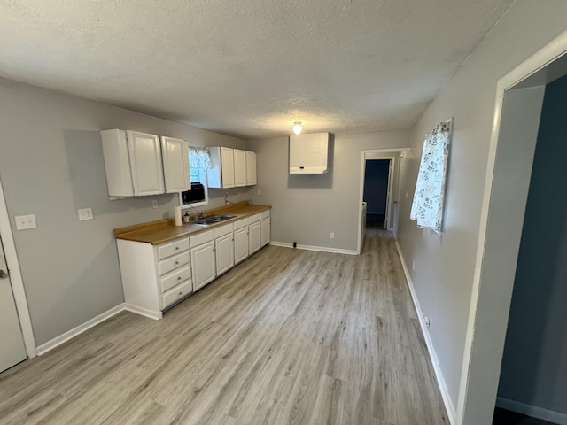 357 Powell Rd, Clay City, KY 40312 - kitchen featuring a textured ceiling, white cabinets, light wood-style flooring, baseboards, and a sink
