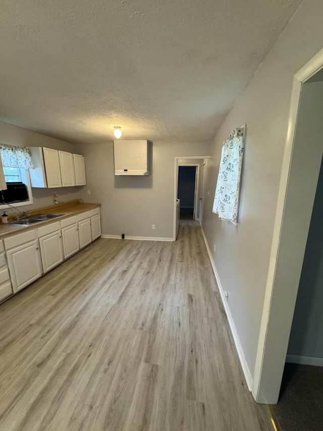 357 Powell Rd, Clay City, KY 40312 - kitchen featuring white cabinetry, a sink, light wood-type flooring, baseboards, and a textured ceiling