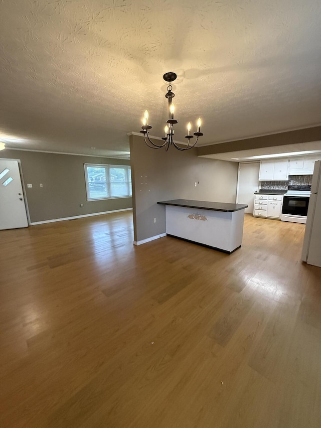 unfurnished dining area featuring a chandelier, light wood-style flooring, baseboards, and a textured ceiling