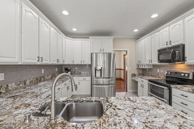 kitchen with stainless steel appliances, a sink, backsplash, light stone countertops, and white cabinets