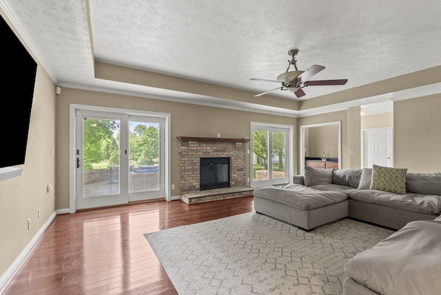 living area featuring a raised ceiling, plenty of natural light, a textured ceiling, and wood finished floors
