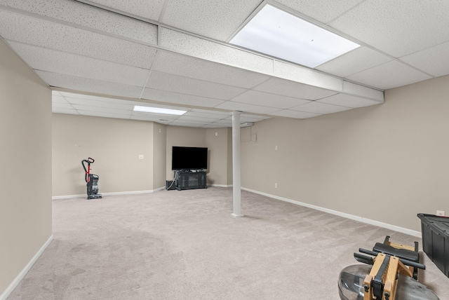 finished below grade area with a paneled ceiling, carpet flooring, and baseboards